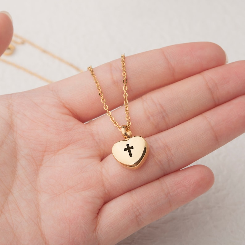 May include: Gold chain necklace with a heart-shaped pendant featuring a cross cutout.