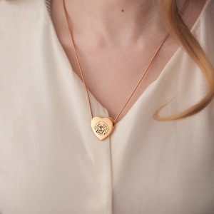 May include: A gold heart-shaped pendant necklace with a dog's face engraved on it.