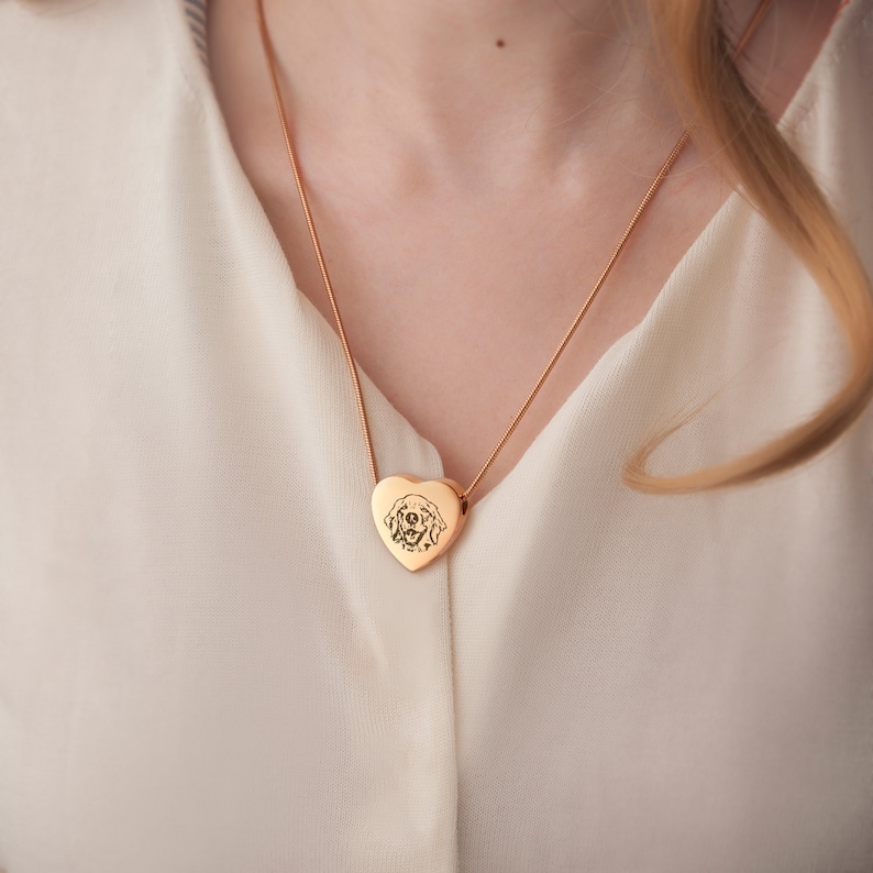 May include: A gold heart-shaped pendant necklace with a dog's face engraved on it.