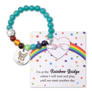 May include: A turquoise beaded bracelet with a charm featuring a paw print and a dog's face. The charm also has the name "Benji" engraved on it. The bracelet comes with a card that reads "I'm at the Rainbow Bridge where I will wait and play, until we meet another day."