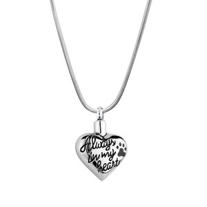 May include: Silver heart-shaped cremation necklace with a paw print and the inscription "Always in my heart".