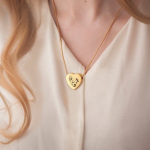 May include: A gold heart-shaped pendant necklace with a photo of a dog engraved on the front.