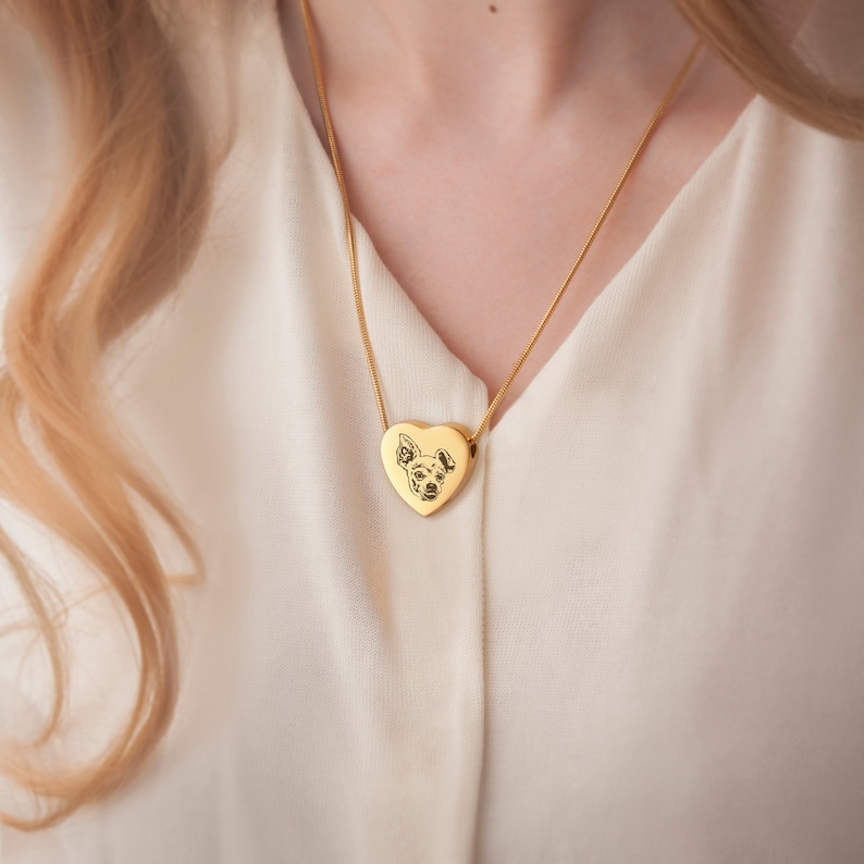 May include: A gold heart-shaped pendant necklace with a photo of a dog engraved on the front.