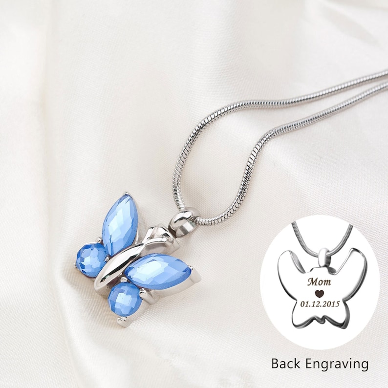 May include: Silver chain necklace with a blue crystal butterfly pendant. The back of the pendant is engraved with "Mom" and a date.