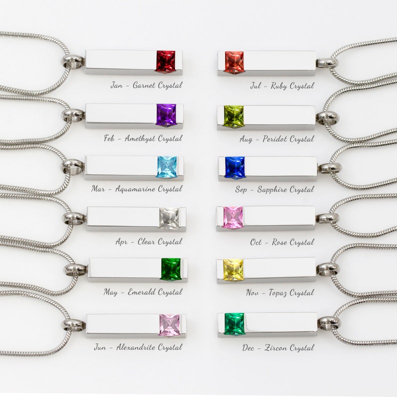 May include: Twelve silver necklaces with a bar pendant and a colored crystal. Each necklace is labeled with a month and the corresponding birthstone.  Jan - Garnet Crystal, Jul - Ruby Crystal, Feb - Amethyst Crystal, Aug - Peridot Crystal, Mar - Aquamarine Crystal, Sep - Sapphire Crystal, Apr - Clear Crystal, Oct - Rose Crystal, May - Emerald Crystal, Nov - Topaz Crystal, Jun - Alexandrite Crystal, Dec - Zircon Crystal.