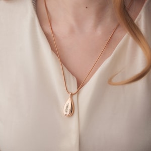 May include: A rose gold necklace with a teardrop pendant featuring a delicate tree design.