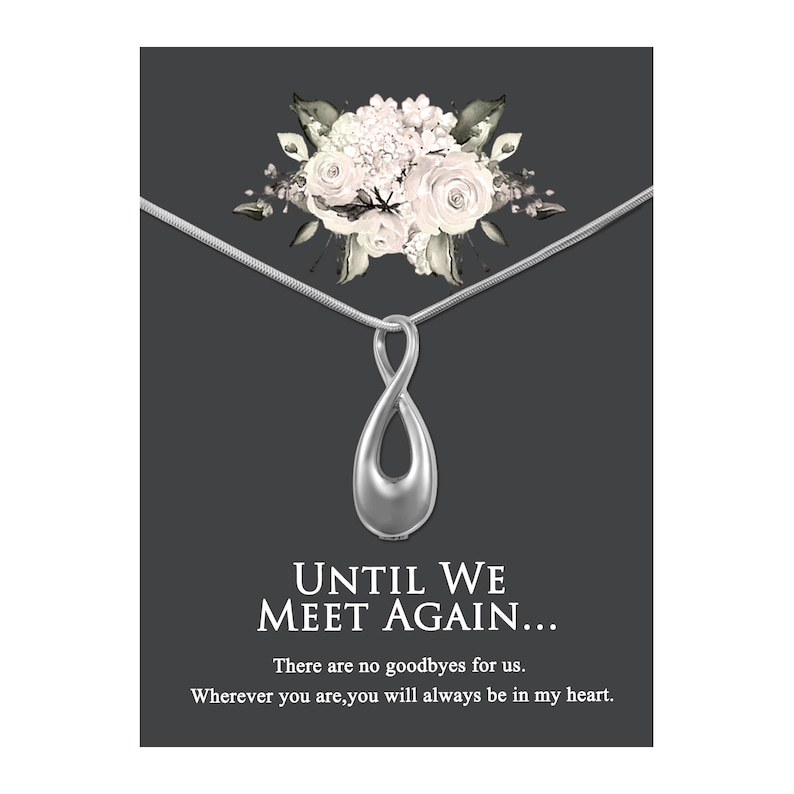 May include: Silver infinity pendant necklace with a floral design. The pendant has a small opening for ashes or other keepsakes. The necklace comes with a card that reads "Until We Meet Again... There are no goodbyes for us. Wherever you are, you will always be in my heart."