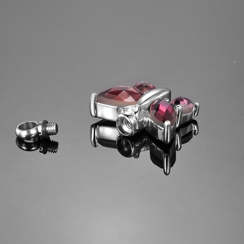 May include: A silver pendant with a red butterfly design. The pendant has a screw-on top and is attached to a silver chain.