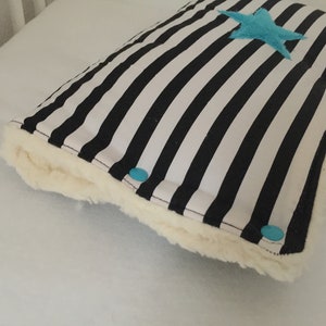 Könnte beinhalten: Ein schwarz-weiß gestreiftes Kissen mit einem blauen Stern in der Mitte. Das Kissen ist mit weißem Kunstfell eingefasst.