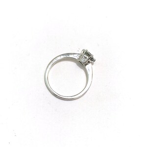 Op de afbeelding: Een zilveren ring met een enkele ronde diamant in een kraalbezetting.