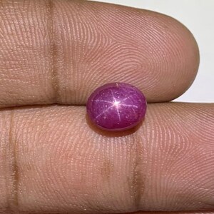 May include: A round, pink star ruby gemstone with a six-pointed star in the center.