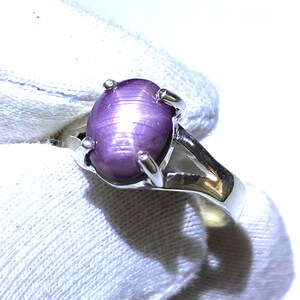 Könnte beinhalten: Ein silberner Ring mit einem großen, ovalen, violetten Sternrubin.