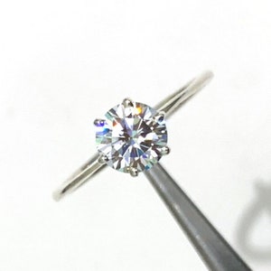 Op de afbeelding: Een zilveren ring met een grote, heldere, ronde diamant.