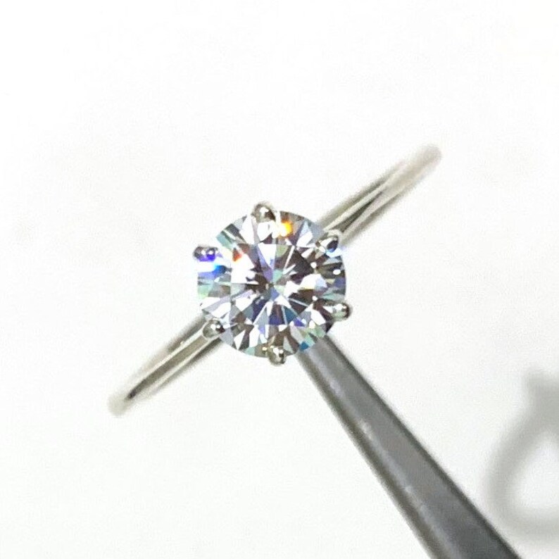 Op de afbeelding: Een zilveren ring met een grote, heldere, ronde diamant.