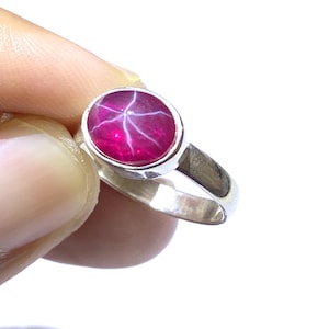 Puede incluir: Un anillo de plata con una piedra preciosa de rubí estrellado rosa.
