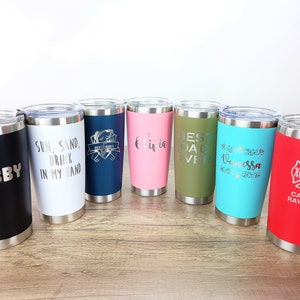 May include: Eight stainless steel tumblers with various colors and personalized engravings. The engravings include "Hubby", "Sun, Sand, Drink in my Hand", "Best Dad Ever", "Vanessa", and "Captain Ray Wade".