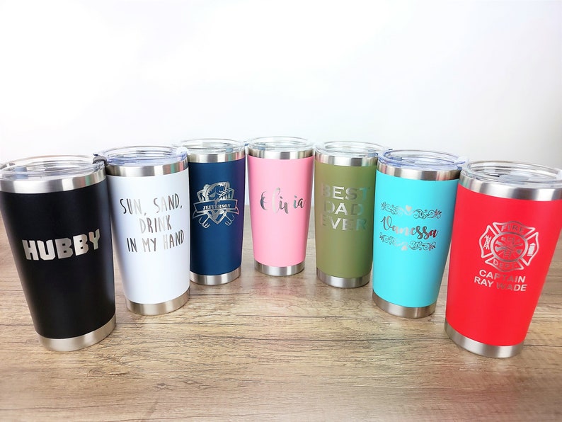 May include: Eight stainless steel tumblers with various colors and personalized engravings. The engravings include "Hubby", "Sun, Sand, Drink in my Hand", "Best Dad Ever", "Vanessa", and "Captain Ray Wade".