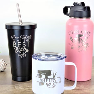 Puede incluir: Tres vasos de acero inoxidable con grabados personalizados. El vaso negro tiene el texto "Hair Stylists Give the Best Blow Jobs". El vaso blanco tiene un secador de pelo, tijeras y peines con el nombre "Shelby" grabado. El vaso rosa tiene un secador de pelo, tijeras y peines con el nombre "Charlotte" grabado.