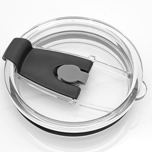 May include: A clear plastic lid with a black slider and a gray button. The lid is designed for a tumbler or cup.