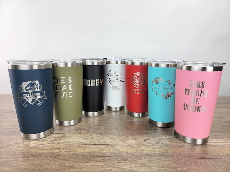 May include: Eight stainless steel tumblers with various colors and personalized engravings. The engravings include "Jefferson", "Best Dad Ever", "Hubby", "Elizabeth", "Captain Ray Wade", "Andrea", and "This Might Be Vodka".