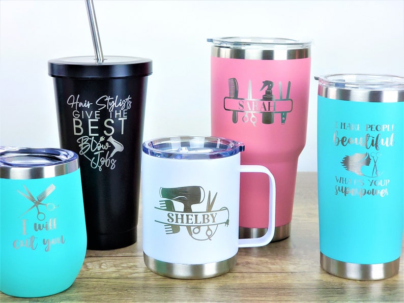 Puede incluir: Cinco vasos de acero inoxidable con diferentes dise&ntilde;os y textos. Los vasos son de diferentes colores, incluyendo negro, blanco, rosa y turquesa. El texto en los vasos incluye "Hair Stylists Give the Best Blow Jobs", "I will cut you", "SHELBY", "SARAH", y "I make people beautiful. What's your superpower?"