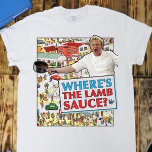 May include: White t-shirt with a graphic of a chef holding a pot and a sign that says "Where's the Lamb Sauce?" The chef is wearing a white chef's uniform and has a surprised expression on his face.