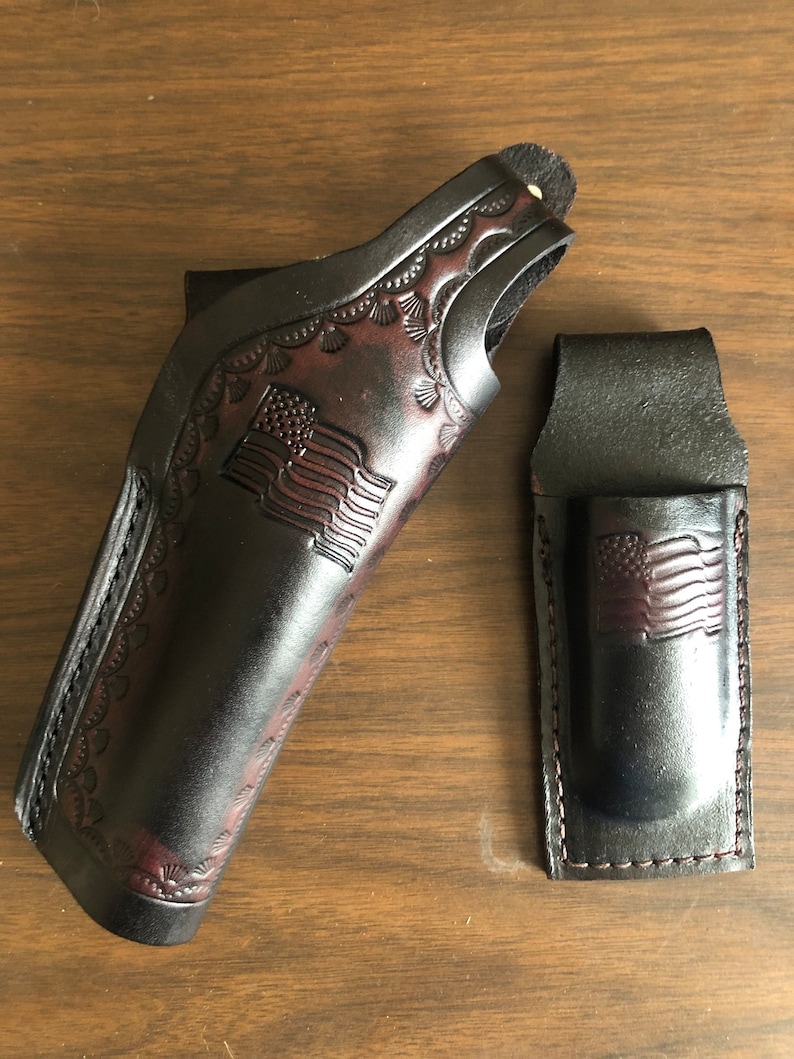 Puede incluir: Dos fundas de cuero negro con un dise&ntilde;o de bandera estadounidense. La funda m&aacute;s grande tiene un borde decorativo, mientras que la funda m&aacute;s peque&ntilde;a tiene un dise&ntilde;o sencillo.