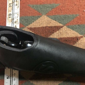 Pode incluir: Um coldre de couro preto para uma pistola. O coldre &eacute; projetado para se ajustar perfeitamente &agrave; arma e tem uma aba que cobre o gatilho.