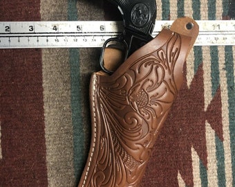Funda de cuero con cierre de pulgar y diseño floral marrón. Compatible con Ruger Wrangler Single Six y Ten 22Cal Uberti Stallion +