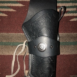 Peut inclure: Un &eacute;tui en cuir noir avec un motif floral et un bouton en m&eacute;tal argent&eacute;. L'&eacute;tui est dot&eacute; d'une sangle et d'une boucle pour l'attacher &agrave; une ceinture.