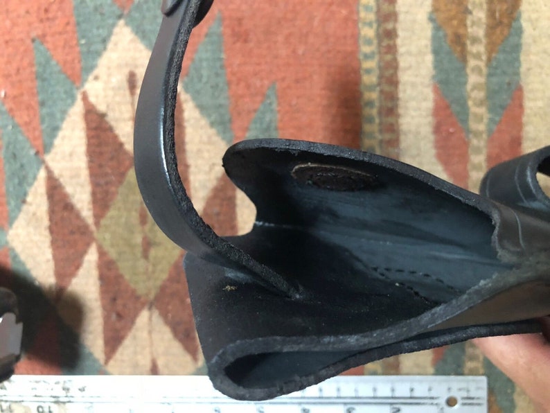 May include: Close-up of the inside of a black leather holster. The holster is made of thick leather and has a smooth finish. The inside of the holster is lined with a soft material.