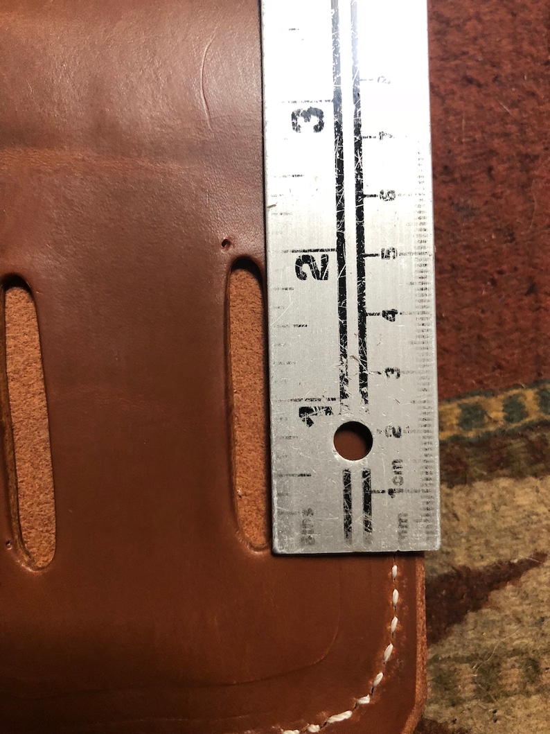 May include: A brown leather wallet with a white stitch detail and a ruler measuring 3 cm in length.