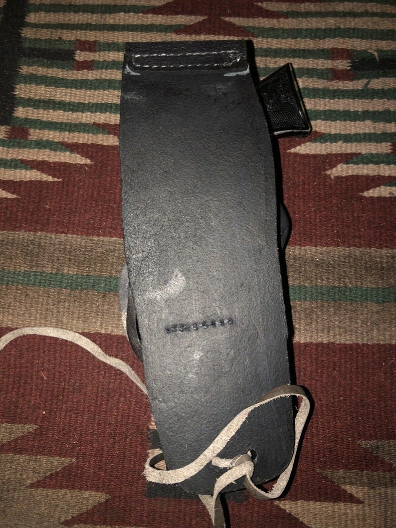Peut inclure: Une sangle de guitare en cuir noir avec une sangle en cuir blanc attach&eacute;e. La sangle est sur un tapis &agrave; motifs.