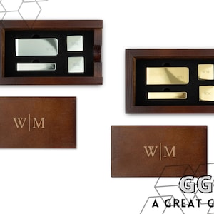 May include: Two wooden boxes with engraved initials "W|M" and a set of silver and gold money clips and cufflinks inside. The boxes are on a white background.