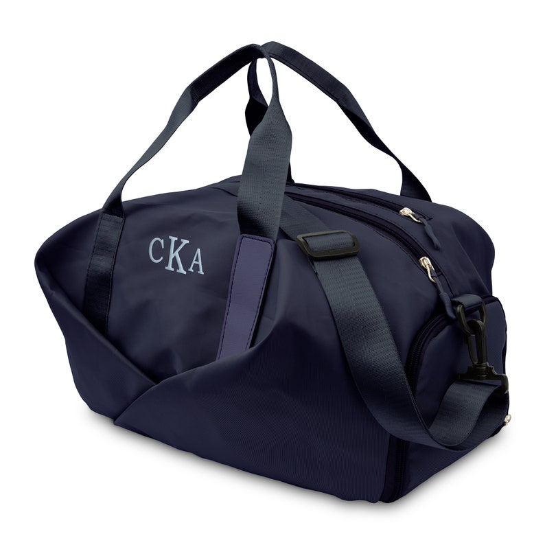 May include: A navy blue duffel bag with a zippered closure and a shoulder strap. The bag has a monogrammed "CKA" on the front.