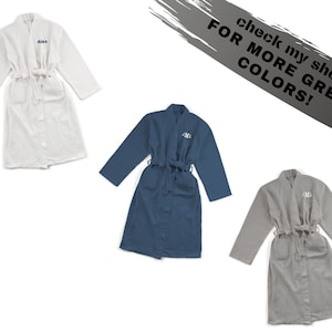May include: Three personalized bathrobes in white, blue, and gray. Each robe has a different name embroidered on the front. The text "check my shop for more great colors!" is written in black on a gray background.