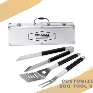 Può includere: Un set di utensili da barbecue personalizzato con una valigetta in metallo argentato e quattro utensili in acciaio inossidabile con manici neri. La valigetta è etichettata "WILLIAM GRILL MASTER". È visibile anche il testo "CUSTOMIZED BBQ TOOL SET".