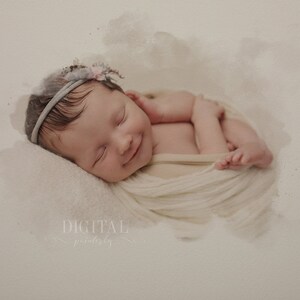 May include: A newborn baby girl sleeping peacefully in a white swaddle, wearing a light blue headband with a floral accent. The baby is smiling softly and has a light complexion.