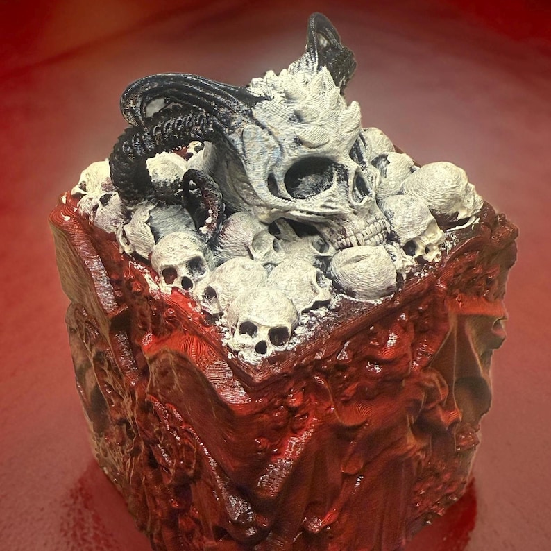 Puede incluir: Un cubo impreso en 3D con un cr&aacute;neo y cuernos en la parte superior. El cubo est&aacute; cubierto de cr&aacute;neos m&aacute;s peque&ntilde;os y est&aacute; pintado en tonos de rojo y blanco.