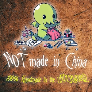 Puede incluir: Un monstruo verde de dibujos animados con tent&aacute;culos est&aacute; cosiendo una bolsa de tela rosa. El monstruo est&aacute; rodeado de materiales de arte, incluyendo pinceles, pintura y una mu&ntilde;eca de madera. El texto "NOT made in China" y "100% Handmade in the UNDERWORLD" est&aacute; escrito debajo del monstruo.