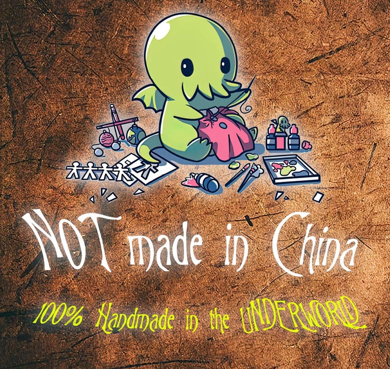 Puede incluir: Un monstruo verde de dibujos animados con tent&aacute;culos est&aacute; cosiendo una bolsa de tela rosa. El monstruo est&aacute; rodeado de materiales de arte, incluyendo pinceles, pintura y una mu&ntilde;eca de madera. El texto "NOT made in China" y "100% Handmade in the UNDERWORLD" est&aacute; escrito debajo del monstruo.