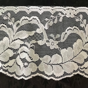 May include: White lace trim with a floral pattern. The lace has a scalloped edge.
