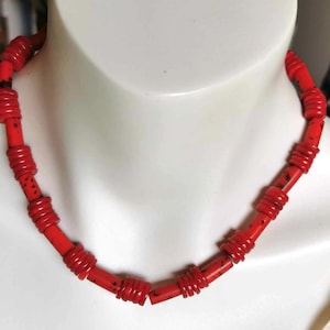 Op de afbeelding: Een rode kralenketting met ronde kralen. De kralen zijn gemaakt van een rood materiaal met een gevlekt patroon.
