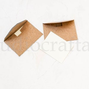 May include: Two brown paper envelopes with a white card inside one of them. The envelopes are on a white background.