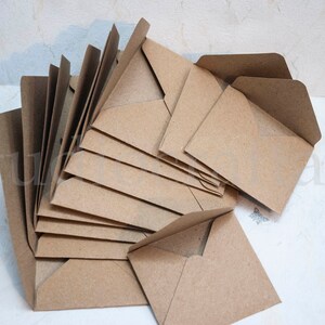 K&ouml;nnte beinhalten: Ein Stapel brauner Kraftpapierumschl&auml;ge. Die Umschl&auml;ge sind gefaltet und bereit zum Versenden von Briefen oder Karten.