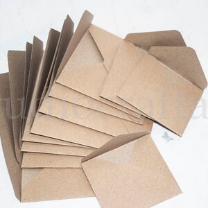 K&ouml;nnte beinhalten: Ein Stapel brauner Kraftpapierumschl&auml;ge mit einer Klappe oben. Die Umschl&auml;ge sind f&auml;cherf&ouml;rmig angeordnet.