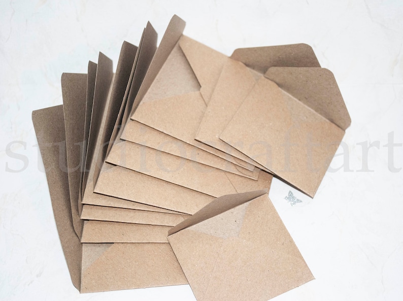 K&ouml;nnte beinhalten: Ein Stapel brauner Kraftpapierumschl&auml;ge mit einer Klappe oben. Die Umschl&auml;ge sind f&auml;cherf&ouml;rmig angeordnet.