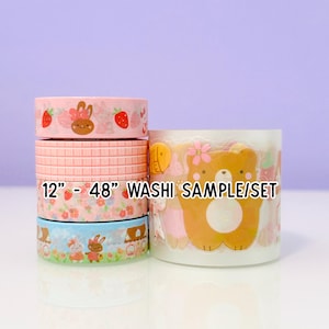 May include: A set of decorative washi tapes with various designs. The tapes include strawberry and bunny patterns, a pink brick pattern, and a blue and green bunny scene. The text "12" - "48" WASHi SAMPLE/SET" is visible.