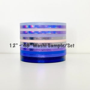 May include: A stack of eight different colored washi tapes in shades of purple, blue, and pink. The tapes are 12" - 48" washi sample/set.