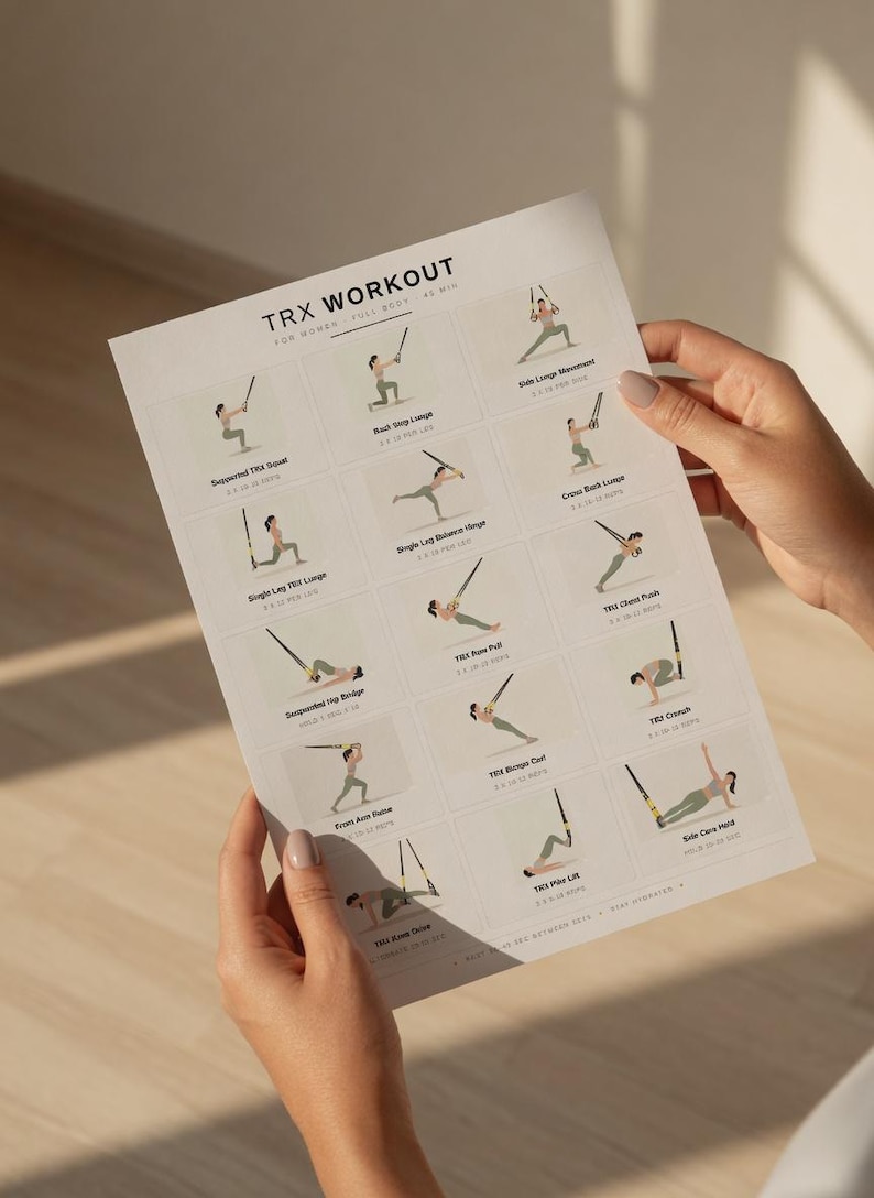 May include: A white printed workout guide titled "TRX WORKOUT FOR WOMEN FULL BODY - AS MIN". The guide displays illustrated exercises with instructions. The guide is held by a person with manicured nails.